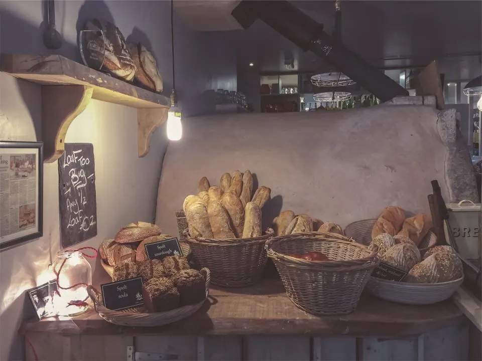 Wooden bakery shelves stacked with loaves and baskets of bread